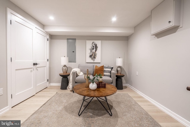 sitting room featuring electric panel, light wood-style flooring, and baseboards