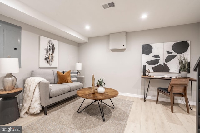 living area with electric panel, baseboards, visible vents, light wood-style floors, and recessed lighting