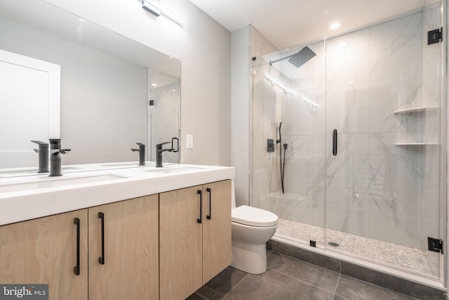 bathroom featuring double vanity, a marble finish shower, a sink, and toilet