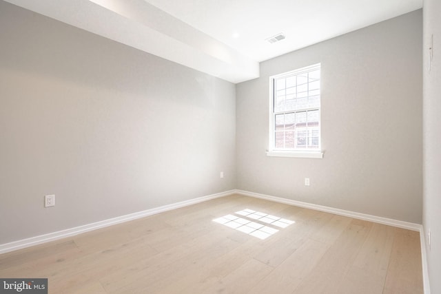 empty room featuring baseboards, visible vents, and light wood finished floors