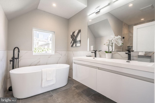 full bathroom featuring a soaking tub, vaulted ceiling, a sink, and double vanity