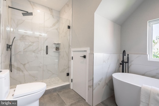 bathroom featuring a wainscoted wall, a marble finish shower, a soaking tub, toilet, and vaulted ceiling