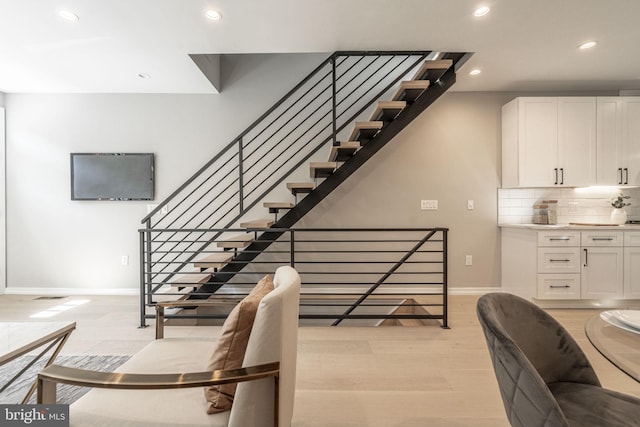 stairway featuring baseboards, wood finished floors, and recessed lighting