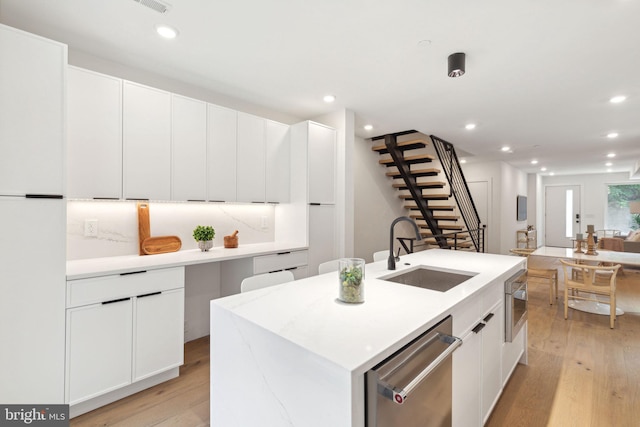 kitchen featuring dishwasher, a kitchen island with sink, light wood-type flooring, a sink, and recessed lighting