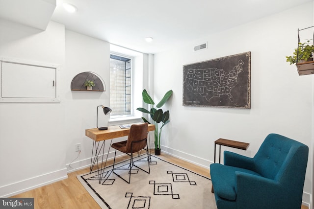 office space featuring wood finished floors, visible vents, and baseboards