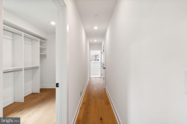 hall with light wood-style floors, recessed lighting, and baseboards