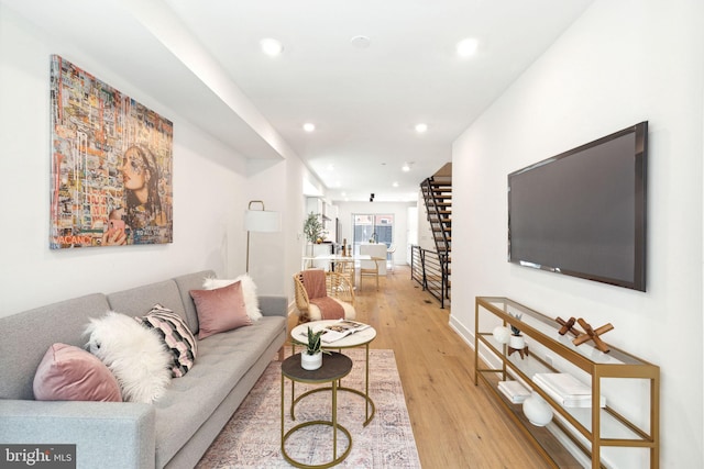 living area featuring baseboards, stairway, light wood-type flooring, and recessed lighting