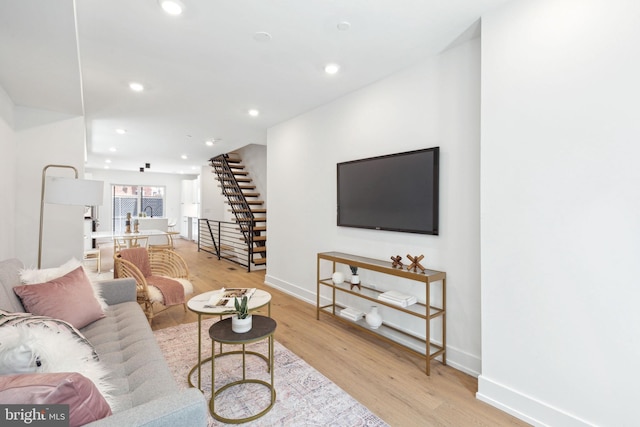 living room with light wood-style floors, recessed lighting, baseboards, and stairs