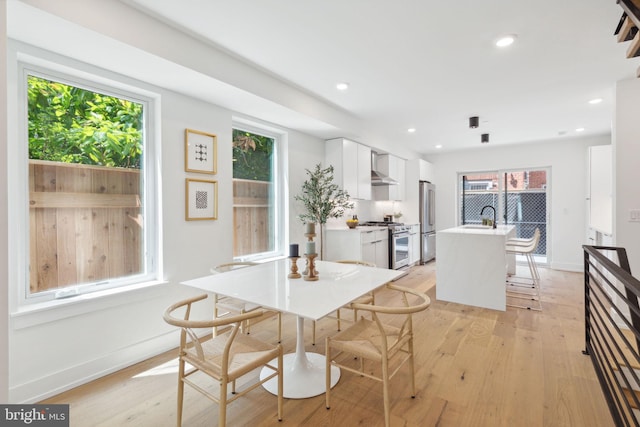 dining area featuring baseboards, light wood-type flooring, and recessed lighting