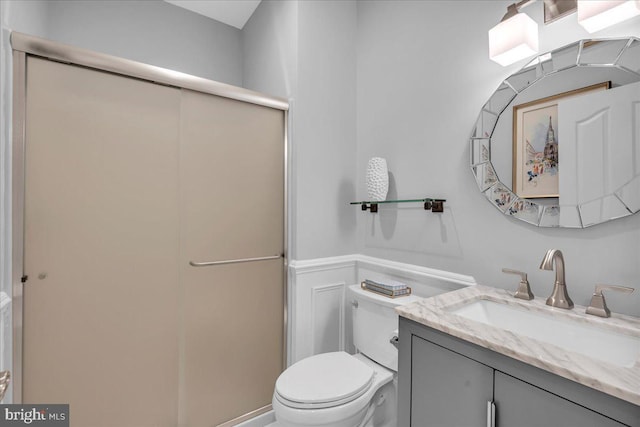 bathroom with a stall shower, vanity, and toilet