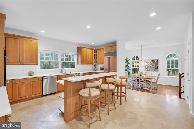 kitchen featuring a sink, a wealth of natural light, light countertops, and dishwasher