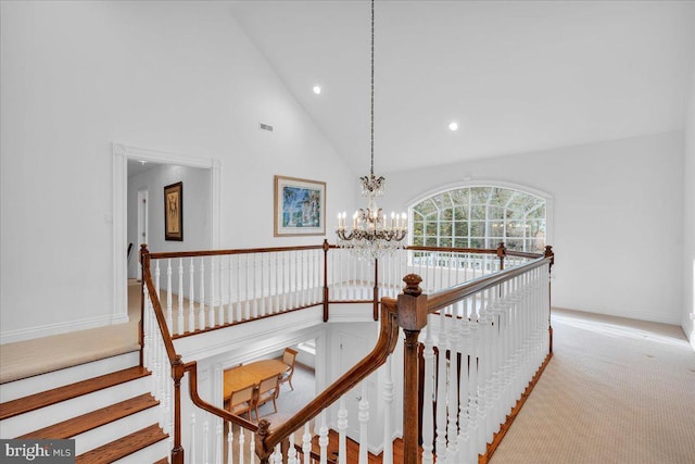 hall featuring high vaulted ceiling, a chandelier, carpet floors, and an upstairs landing