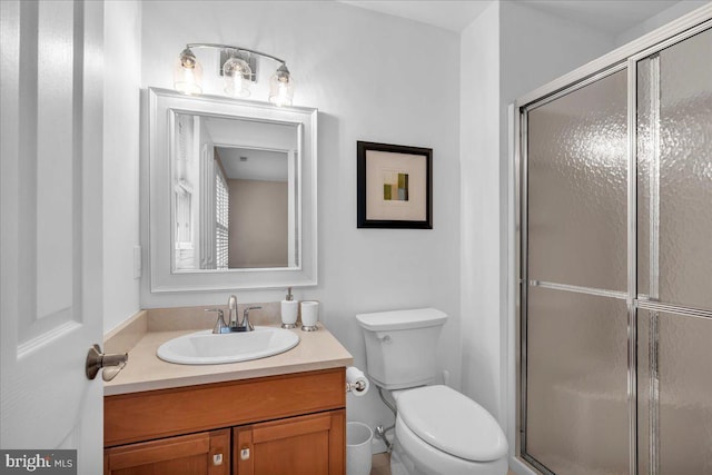 bathroom with toilet, a stall shower, and vanity