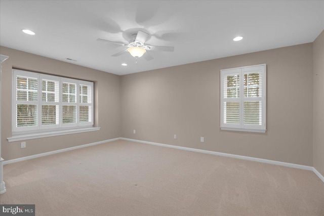 unfurnished room featuring light colored carpet, a healthy amount of sunlight, visible vents, and baseboards