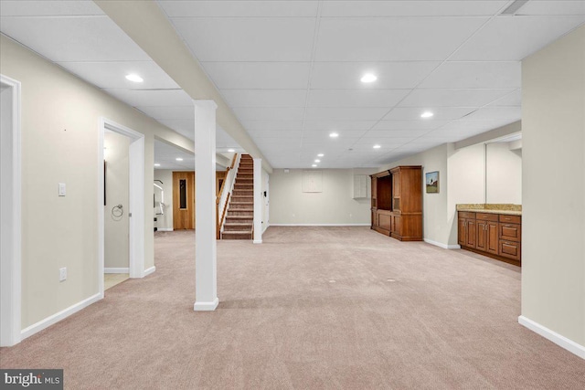 finished basement featuring light carpet, baseboards, stairway, and recessed lighting