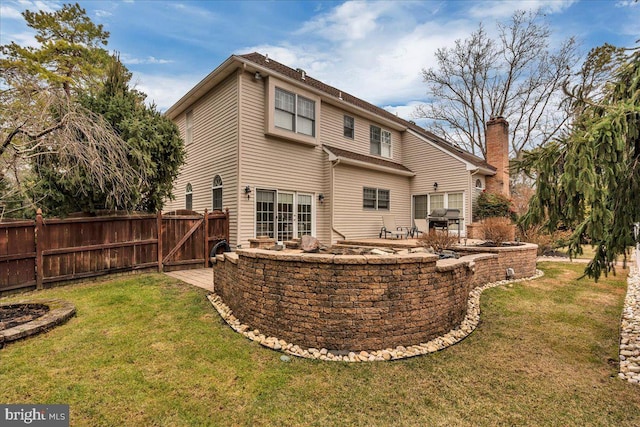 back of property with a yard, a patio area, fence, and a chimney