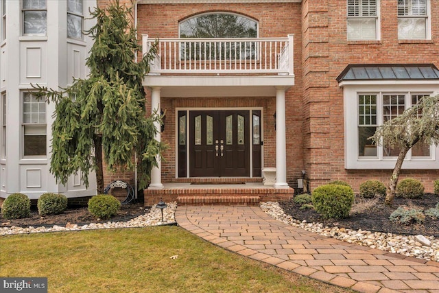 entrance to property featuring a balcony and brick siding