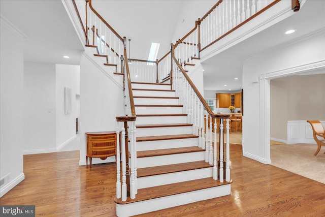 stairs featuring a high ceiling, wood finished floors, and baseboards