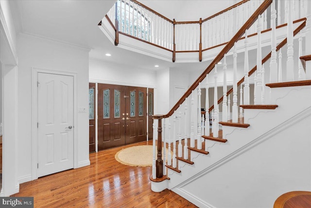 foyer featuring recessed lighting, stairway, a towering ceiling, ornamental molding, and wood finished floors