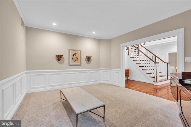 sitting room with a decorative wall, stairway, ornamental molding, and recessed lighting