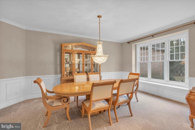 dining area with a chandelier, a wainscoted wall, visible vents, and crown molding