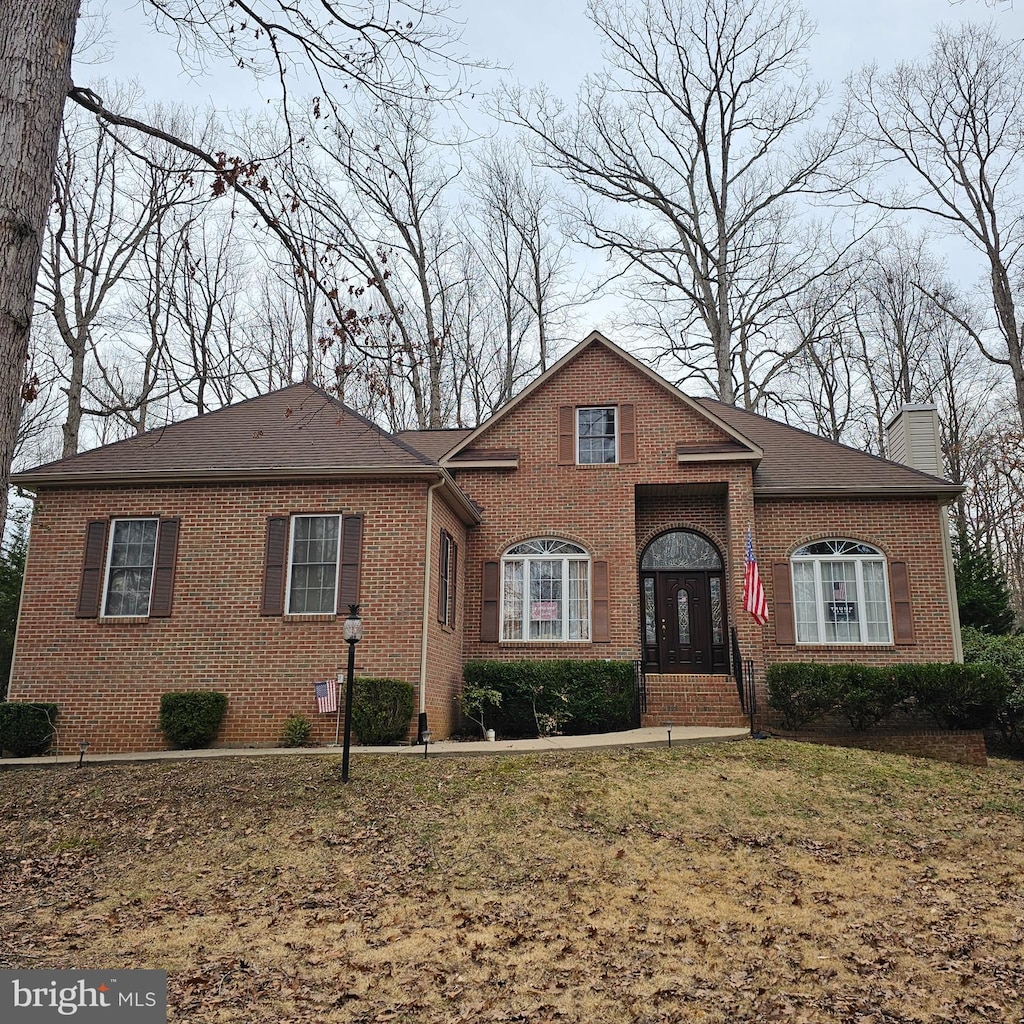 view of front of house with a chimney, a front lawn, and brick siding