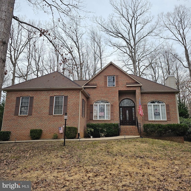 view of front of house with a chimney, a front lawn, and brick siding