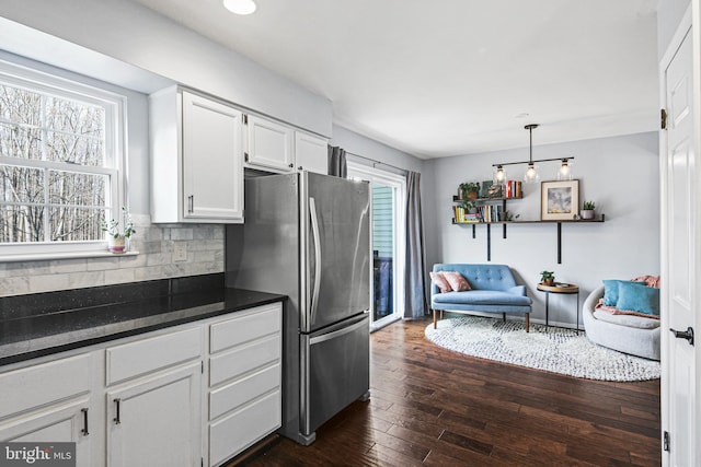 kitchen featuring dark wood-style flooring, freestanding refrigerator, decorative backsplash, white cabinets, and dark countertops