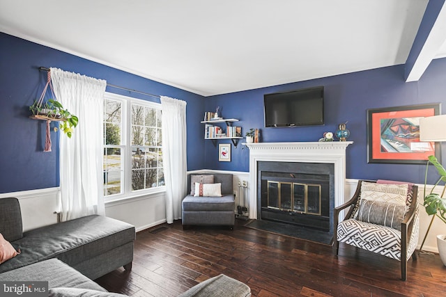 living area featuring a fireplace with flush hearth, baseboards, visible vents, and hardwood / wood-style floors