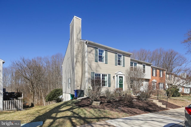 townhome / multi-family property featuring a front lawn and a chimney