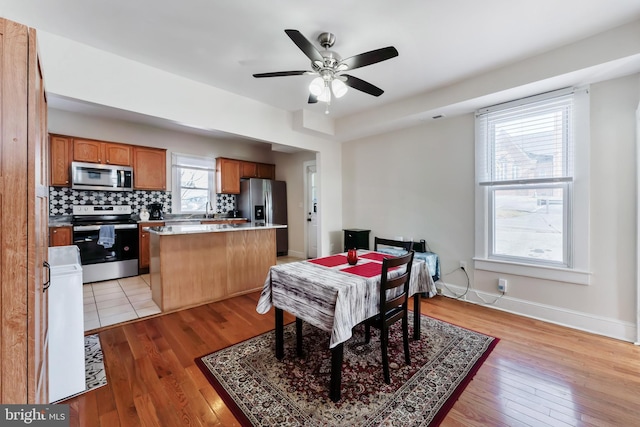 dining room with light wood-style floors, ceiling fan, and baseboards