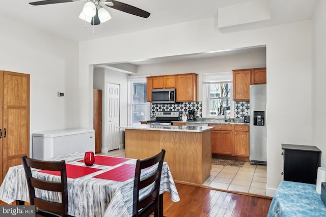 kitchen with backsplash, a kitchen island, stainless steel appliances, and light countertops