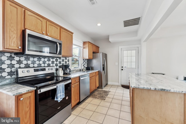 kitchen featuring light tile patterned floors, a sink, visible vents, appliances with stainless steel finishes, and backsplash