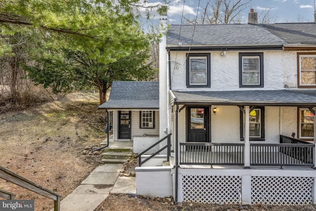 view of front of property with stucco siding, a porch, a chimney, and a shingled roof