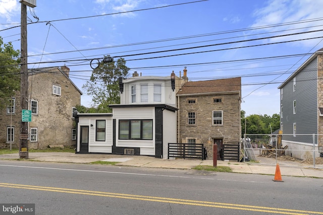 view of front facade with stone siding and fence