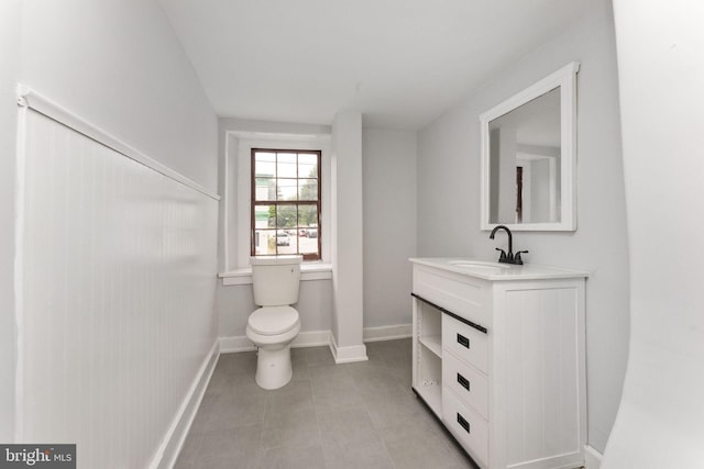 bathroom with toilet, tile patterned flooring, baseboards, and vanity