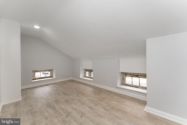 additional living space featuring a healthy amount of sunlight, baseboards, vaulted ceiling, and wood finished floors