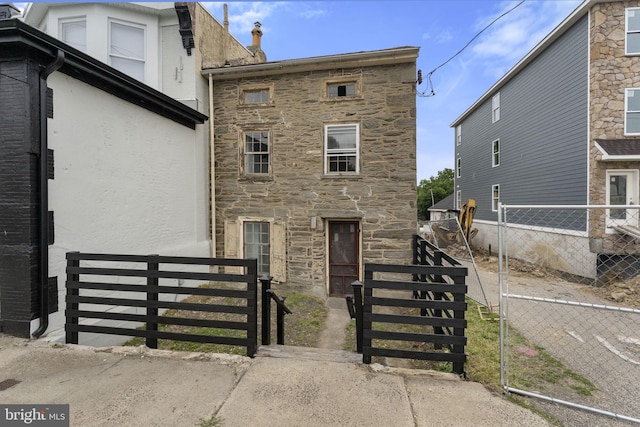 view of front of home featuring stone siding and fence