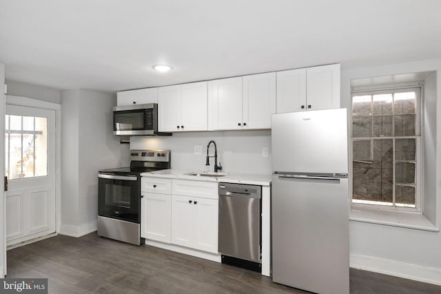 kitchen featuring stainless steel appliances, a sink, a wealth of natural light, and white cabinetry