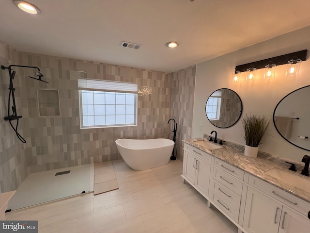 bathroom with a freestanding tub, a sink, visible vents, double vanity, and walk in shower