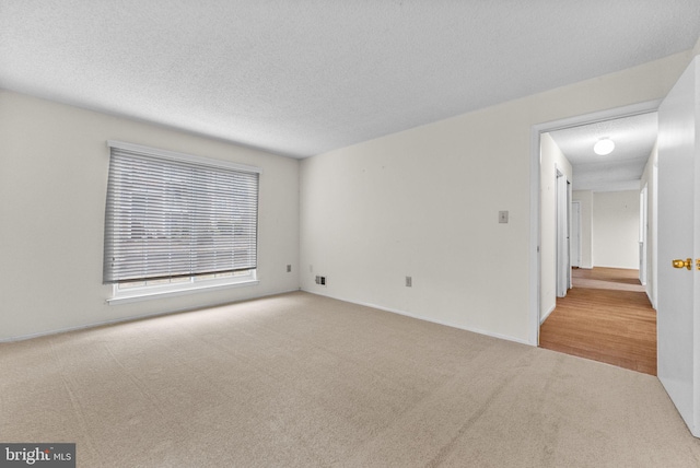 carpeted empty room with a textured ceiling and visible vents