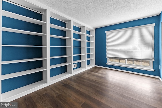 empty room with a textured ceiling and wood finished floors