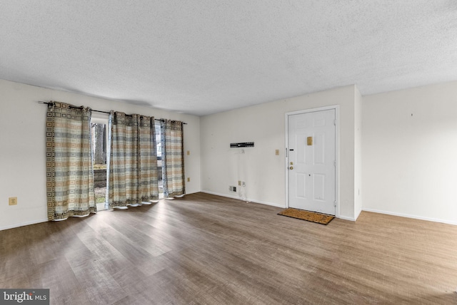 interior space with a textured ceiling, wood finished floors, and baseboards