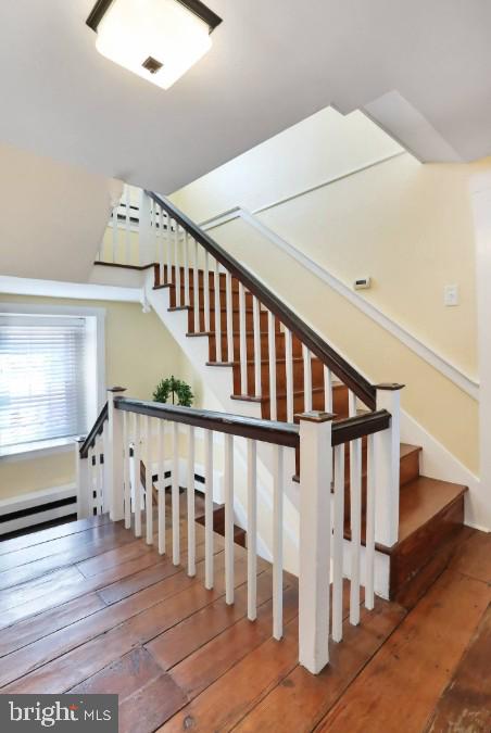 stairway featuring visible vents, a baseboard radiator, and hardwood / wood-style flooring