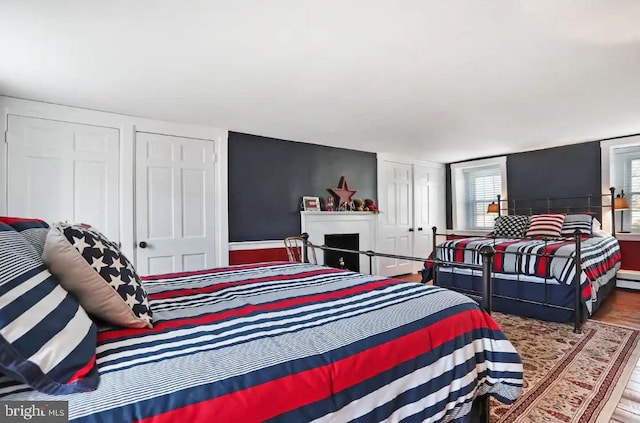 bedroom featuring a baseboard radiator, a fireplace, and wood finished floors