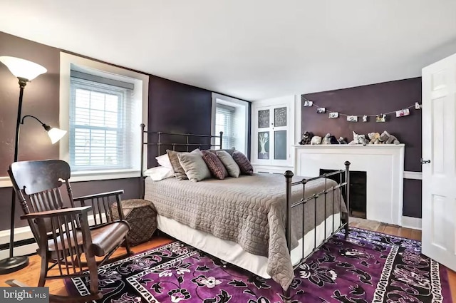 bedroom featuring a fireplace, baseboards, and wood finished floors