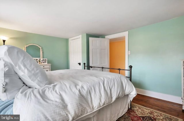 bedroom featuring wood finished floors, baseboards, and a closet