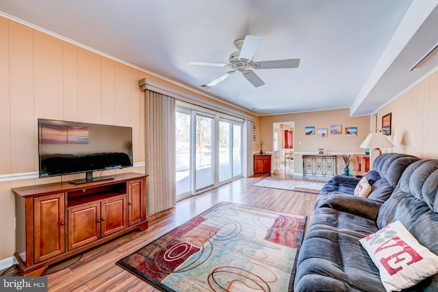 living room featuring light wood-style flooring, ceiling fan, and crown molding