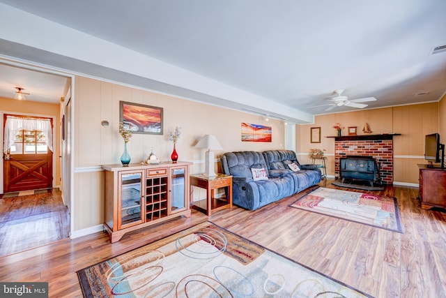 living room with a ceiling fan, visible vents, baseboards, and wood finished floors