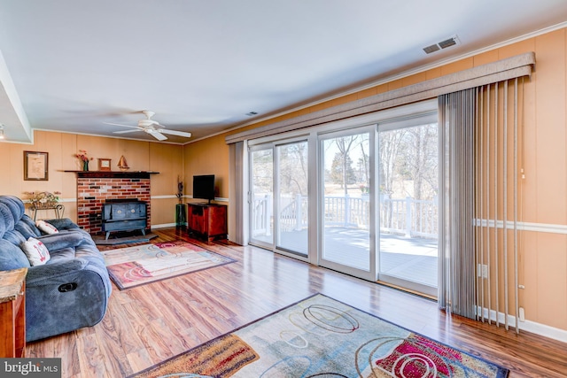 living area with a ceiling fan, crown molding, visible vents, and wood finished floors